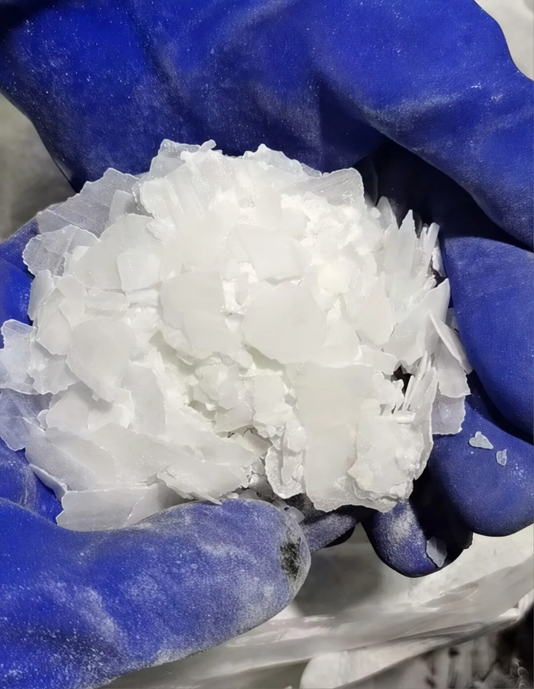 Closeup Kaustik Soda Serpihan dengan Sarung Tangan Pelindung